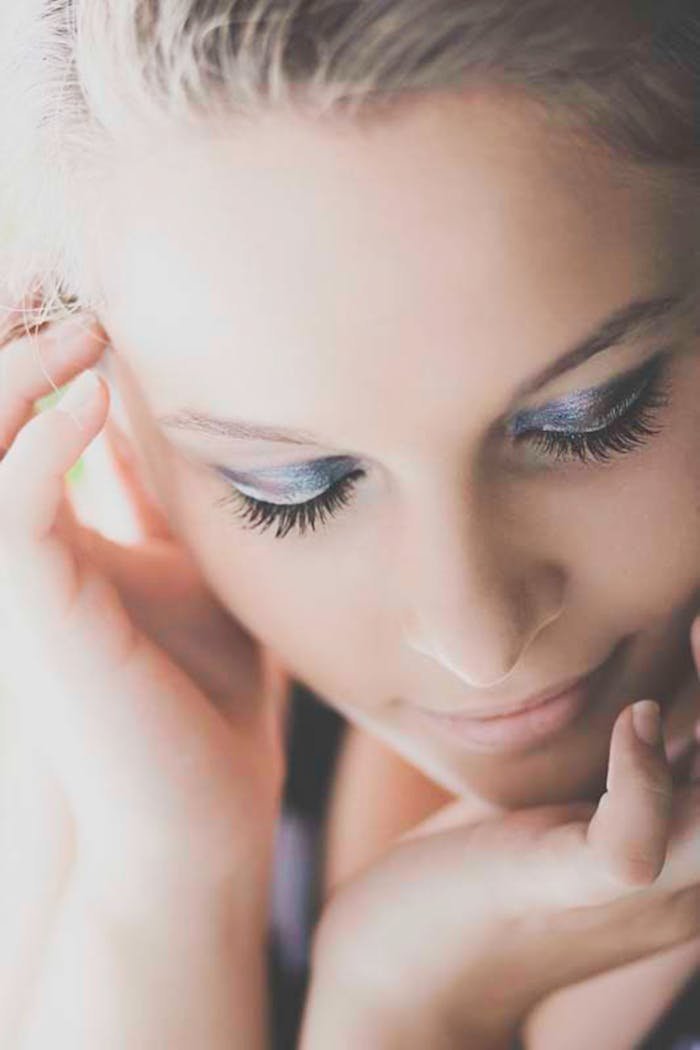 Close-up of a young woman with makeup and eyes closed, exuding elegance.